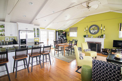 Example of a beach style open concept medium tone wood floor living room design in Boston with green walls, a standard fireplace, a brick fireplace and a tv stand