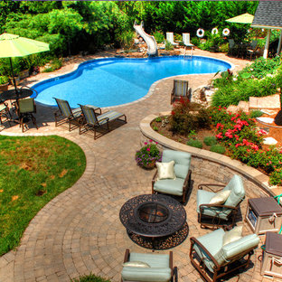 Foto på en mellanstor vintage träningspool på baksidan av huset, med vattenrutschkana och marksten i betong