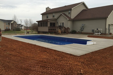 Imagen de piscina rectangular en patio trasero con losas de hormigón