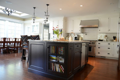 Inspiration for a mid-sized timeless l-shaped medium tone wood floor eat-in kitchen remodel in New York with an undermount sink, recessed-panel cabinets, white cabinets, granite countertops, white backsplash, stainless steel appliances, an island and subway tile backsplash