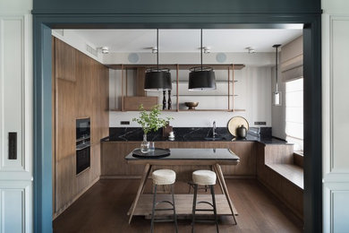 This is an example of a contemporary u-shaped separate kitchen in Moscow with an undermount sink, flat-panel cabinets, medium wood cabinets, black splashback, black appliances, medium hardwood floors, with island, brown floor and black benchtop.
