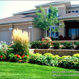 Aménagement d'un jardin avant contemporain l'été avec un mur de soutènement, une exposition ensoleillée et des pavés en béton.