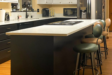 Mid-sized minimalist l-shaped laminate floor and brown floor kitchen pantry photo in Seattle with an undermount sink, recessed-panel cabinets, black cabinets, quartz countertops, white backsplash, quartz backsplash, stainless steel appliances, an island and white countertops