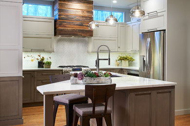 Mid-sized minimalist u-shaped medium tone wood floor and brown floor open concept kitchen photo in Other with an undermount sink, recessed-panel cabinets, beige cabinets, granite countertops, white backsplash, ceramic backsplash, stainless steel appliances, an island and white countertops