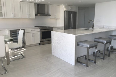 Inspiration for a mid-sized contemporary galley kitchen in Miami with an undermount sink, recessed-panel cabinets, white cabinets, quartzite benchtops, white splashback, stainless steel appliances and grey floor.