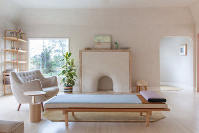Design ideas for a scandinavian living room in Los Angeles with beige walls, light hardwood floors, a standard fireplace, no tv and beige floor.