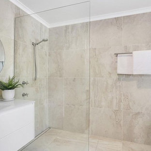Ejemplo de cuarto de baño marinero, de tamaño medio, con armarios con paneles lisos, puertas de armario blancas, bañera exenta, ducha abierta, sanitario de una pieza, baldosas y/o azulejos beige, baldosas y/o azulejos de porcelana, paredes beige, suelo de baldosas de porcelana, lavabo integrado, encimera de vidrio, suelo beige, ducha abierta y encimeras blancas