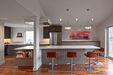 Example of a trendy l-shaped orange floor kitchen design in Seattle with an undermount sink, flat-panel cabinets, stainless steel appliances, an island and white countertops