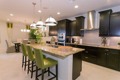 Open concept kitchen - large transitional galley beige floor open concept kitchen idea in Denver with an undermount sink, shaker cabinets, black cabinets, granite countertops, gray backsplash, glass tile backsplash, stainless steel appliances and an island