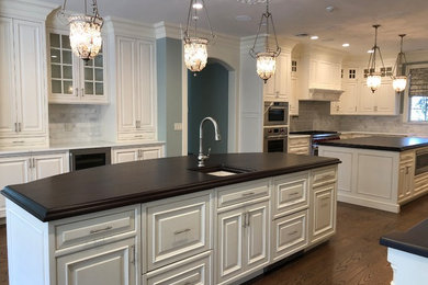 Inspiration for a traditional kitchen in New York with raised-panel cabinets, wood benchtops, multiple islands and brown benchtop.