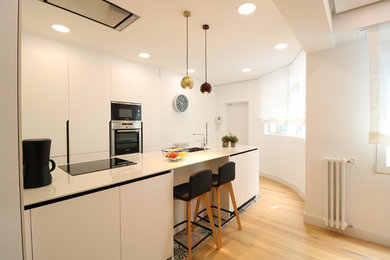 Idéer för stora funkis linjära vitt kök och matrum, med en undermonterad diskho, luckor med infälld panel, vita skåp, integrerade vitvaror, ljust trägolv och en halv köksö