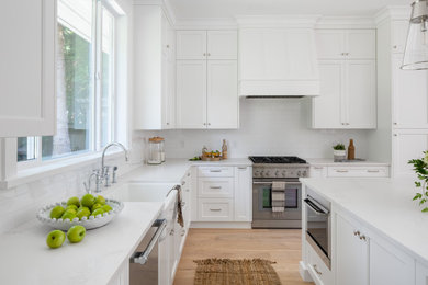 Kitchen - mid-sized transitional l-shaped light wood floor kitchen idea in Vancouver with a farmhouse sink, white backsplash, an island and white countertops
