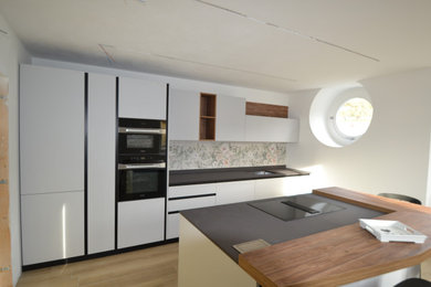 Foto di una grande cucina minimalista chiusa con lavello sottopiano, ante lisce, ante grigie, top in quarzite, paraspruzzi grigio, paraspruzzi con piastrelle in ceramica, elettrodomestici neri, pavimento in gres porcellanato, pavimento grigio e top grigio