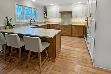 Example of a large u-shaped light wood floor and brown floor eat-in kitchen design in Philadelphia with an undermount sink, shaker cabinets, medium tone wood cabinets, quartzite countertops, brown backsplash, paneled appliances, a peninsula and brown countertops