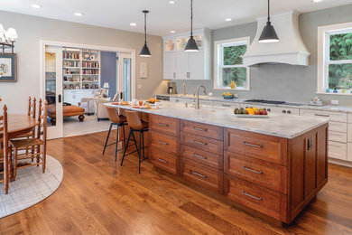 Example of a large transitional l-shaped medium tone wood floor and brown floor enclosed kitchen design with an island, a single-bowl sink, recessed-panel cabinets, white cabinets, marble countertops, green backsplash, glass tile backsplash, paneled appliances and white countertops