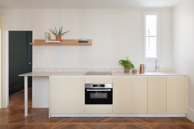 Idée de décoration pour une cuisine ouverte linéaire design de taille moyenne avec un plan de travail en terrazzo, un électroménager en acier inoxydable, parquet foncé, un sol marron, un plan de travail blanc, un évier encastré, des portes de placard jaunes et aucun îlot.