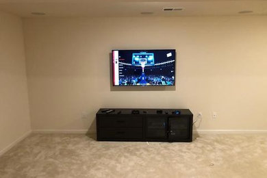 Home theater - large modern enclosed carpeted and beige floor home theater idea in Philadelphia with white walls and a wall-mounted tv