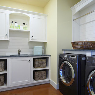 グランドラピッズの大きいトラディショナルスタイルのおしゃれなランドリールーム (黄色い壁、アンダーカウンターシンク、白いキャビネット、御影石カウンター、左右配置の洗濯機・乾燥機、シェーカースタイル扉のキャビネット) の写真