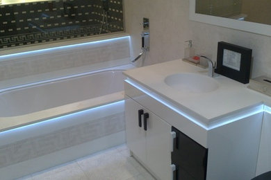 Photo of a medium sized modern family bathroom in London with white cabinets, a built-in bath, beige tiles, porcelain tiles, beige walls, porcelain flooring, a built-in sink and beige floors.