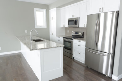 Example of a small arts and crafts single-wall light wood floor eat-in kitchen design in Other with a double-bowl sink, shaker cabinets, white cabinets, granite countertops, gray backsplash, matchstick tile backsplash, stainless steel appliances and an island