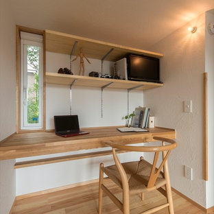 Photo of a small world-inspired home office and library in Yokohama with white walls, medium hardwood flooring, a built-in desk and brown floors.