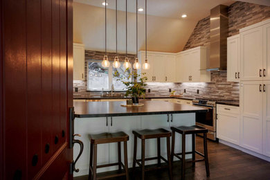 Photo of a large rustic l-shaped kitchen in Los Angeles with a submerged sink, shaker cabinets, granite worktops, grey splashback, porcelain splashback, stainless steel appliances, an island and black worktops.