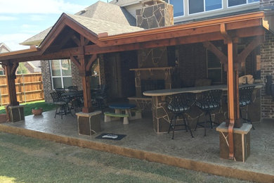 Example of a large mountain style backyard stamped concrete patio design in Dallas with a roof extension