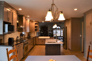 Open concept kitchen - large u-shaped ceramic tile and beige floor open concept kitchen idea in New York with a double-bowl sink, recessed-panel cabinets, brown cabinets, solid surface countertops, white backsplash, ceramic backsplash, stainless steel appliances, an island and brown countertops