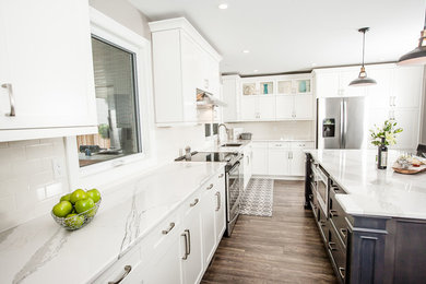 Large contemporary l-shaped eat-in kitchen in Toronto with an undermount sink, shaker cabinets, white cabinets, quartzite benchtops, white splashback, subway tile splashback, stainless steel appliances, dark hardwood floors and with island.