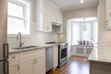 Enclosed kitchen - small traditional galley medium tone wood floor and brown floor enclosed kitchen idea in Other with a double-bowl sink, shaker cabinets, white cabinets, granite countertops, white backsplash, ceramic backsplash, stainless steel appliances, no island and multicolored countertops