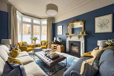 Medium sized classic enclosed living room in Other with blue walls, carpet, a standard fireplace, a wooden fireplace surround, a freestanding tv and panelled walls.