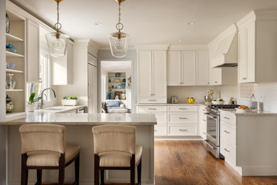 Mid-sized transitional l-shaped medium tone wood floor enclosed kitchen photo in New York with an undermount sink, recessed-panel cabinets, beige cabinets, quartzite countertops, yellow backsplash, subway tile backsplash, paneled appliances, a peninsula and beige countertops