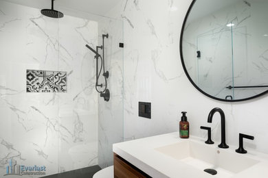 Example of a large minimalist master white tile and marble tile porcelain tile and white floor freestanding bathtub design in San Francisco with flat-panel cabinets, medium tone wood cabinets, a wall-mount toilet, a drop-in sink, quartz countertops, a hinged shower door and white countertops