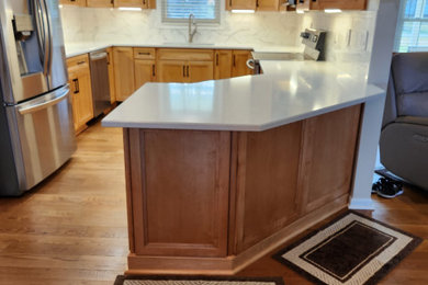 Inspiration for a large transitional u-shaped laminate floor and brown floor enclosed kitchen remodel in Louisville with an undermount sink, flat-panel cabinets, light wood cabinets, quartz countertops, white backsplash, ceramic backsplash, stainless steel appliances, a peninsula and white countertops