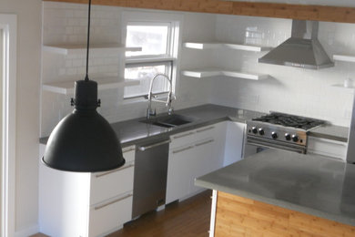 Photo of a medium sized country u-shaped kitchen/diner in Milwaukee with a submerged sink, flat-panel cabinets, white cabinets, concrete worktops, white splashback, metro tiled splashback, stainless steel appliances, bamboo flooring and an island.