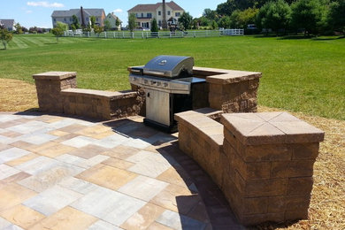 This is an example of a mid-sized traditional backyard full sun garden for summer in Baltimore with natural stone pavers.