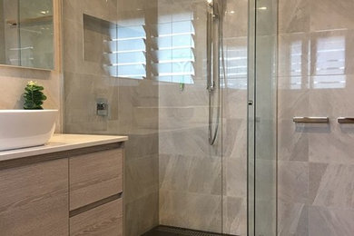 Inspiration for a small modern master bathroom in Brisbane with raised-panel cabinets, light wood cabinets, a corner shower, a wall-mount toilet, gray tile, ceramic tile, grey walls, ceramic floors, soapstone benchtops, brown floor, a sliding shower screen, white benchtops and a wall-mount sink.