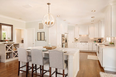 Example of a transitional u-shaped medium tone wood floor kitchen design in Indianapolis with a single-bowl sink, shaker cabinets, white cabinets, marble countertops, gray backsplash, stone tile backsplash, stainless steel appliances and an island