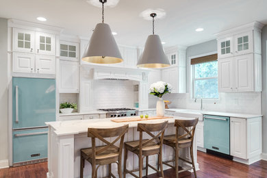 Inspiration for a transitional l-shaped dark wood floor open concept kitchen remodel in Tampa with a farmhouse sink, raised-panel cabinets, white cabinets, marble countertops, white backsplash, subway tile backsplash and an island