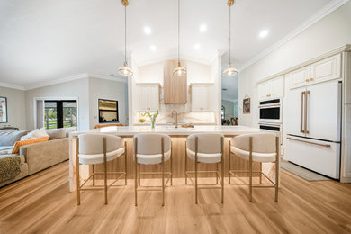 Inspiration for a mid-sized coastal single-wall dark wood floor, brown floor and vaulted ceiling eat-in kitchen remodel in Miami with a drop-in sink, recessed-panel cabinets, beige cabinets, quartz countertops, white backsplash, quartz backsplash, white appliances, an island and white countertops