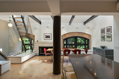 Inspiration for a contemporary light wood floor and beige floor kitchen/dining room combo remodel in New York with white walls, a corner fireplace and a stone fireplace