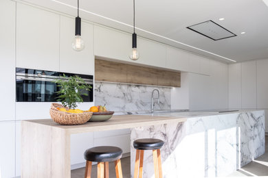 Ejemplo de cocina alargada moderna extra grande abierta con armarios con paneles lisos, electrodomésticos negros, una isla, suelo gris, encimeras blancas y barras de cocina