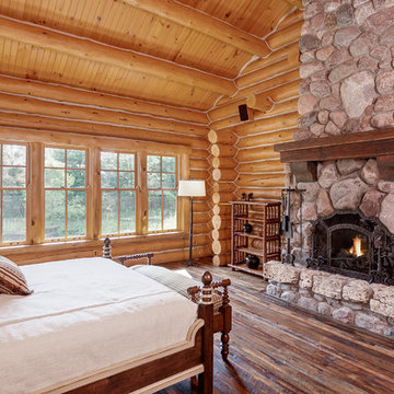 Reclaimed Wood Mantel on Stone Fireplace in Rustic Log Cabin Bedroom