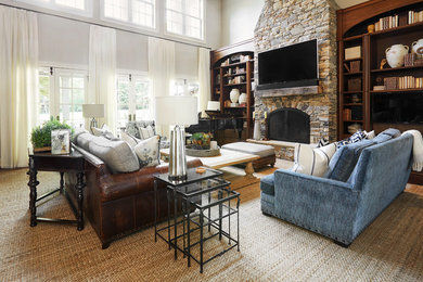 Inspiration for a large traditional open concept living room in Nashville with white walls, light hardwood floors, a standard fireplace, a stone fireplace surround, a wall-mounted tv and brown floor.