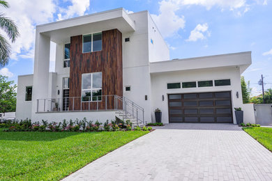 This is an example of a large contemporary two-storey stucco white house exterior in Tampa with a flat roof and a mixed roof.