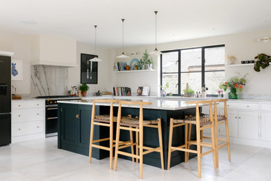 Large contemporary cream and black l-shaped open plan kitchen in Oxfordshire with a built-in sink, flat-panel cabinets, black cabinets, marble worktops, grey splashback, marble splashback, black appliances, marble flooring, an island, white floors and grey worktops.