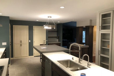 Inspiration for a mid-sized modern u-shaped eat-in kitchen in Minneapolis with an undermount sink, shaker cabinets, dark wood cabinets, quartz benchtops, white splashback, ceramic splashback, stainless steel appliances, with island, grey floor and white benchtop.