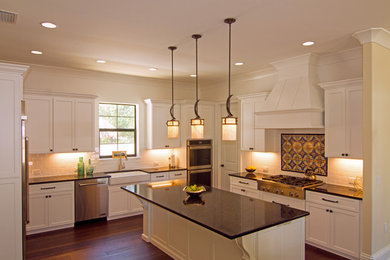 Example of a large transitional porcelain tile and brown floor open concept kitchen design in Tampa with a farmhouse sink, shaker cabinets, white cabinets, quartz countertops, white backsplash, subway tile backsplash, stainless steel appliances, an island and black countertops