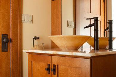Example of a mid-sized mountain style limestone floor bathroom design in Cleveland with shaker cabinets, medium tone wood cabinets, beige walls and a vessel sink