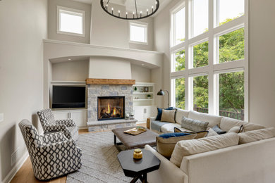 Inspiration for a large enclosed medium tone wood floor, brown floor and coffered ceiling family room remodel in Minneapolis with beige walls, a standard fireplace, a stone fireplace and a media wall